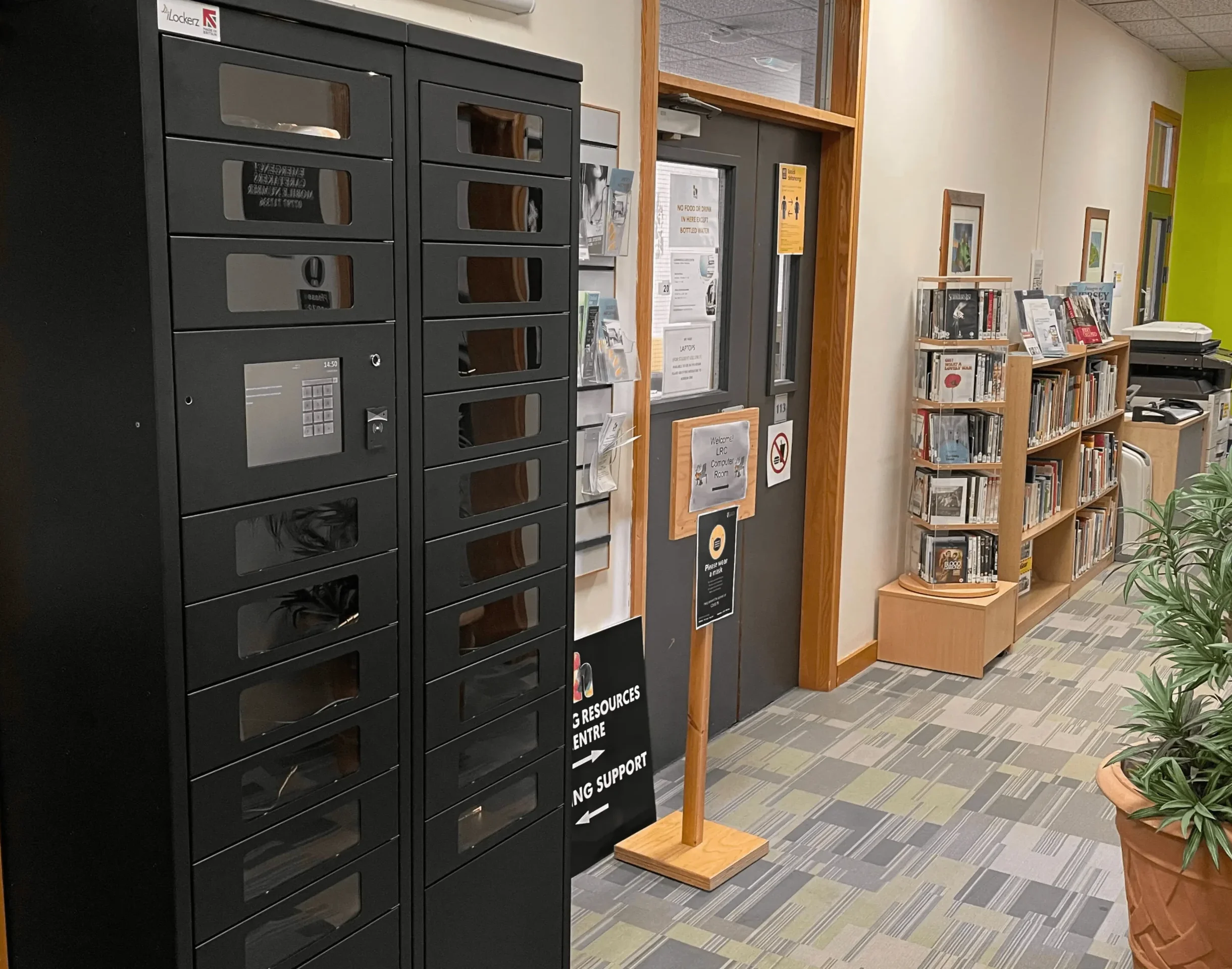 A black iLockerz intelligent locker system installed at Highlands College, featuring transparent compartment windows for visual verification of stored laptops and tablets.