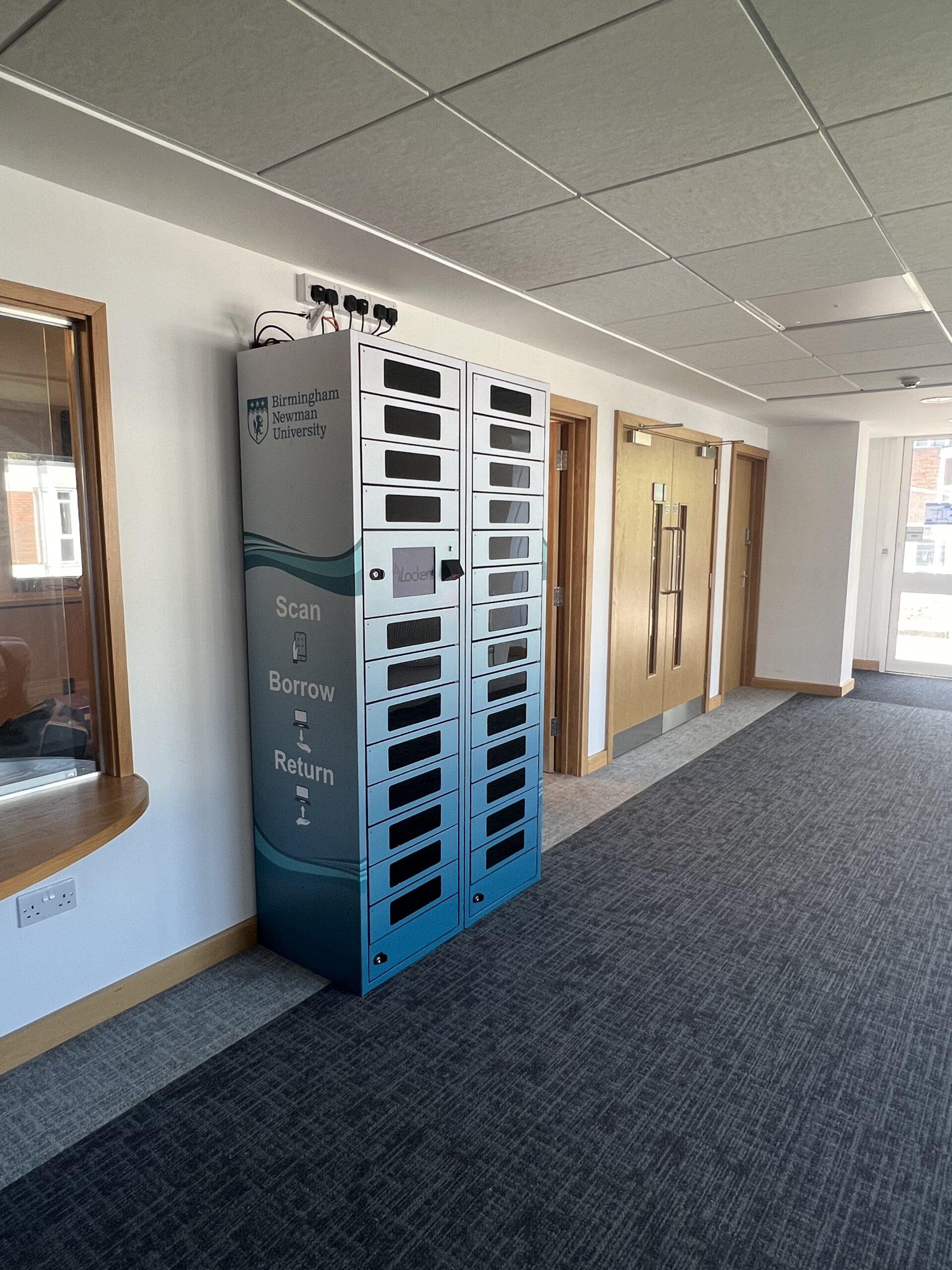 A branded iLockerz laptop loan station at Birmingham Newman University, featuring a "Scan, Borrow, Return" graphic and a touchscreen interface for automated student self-service.