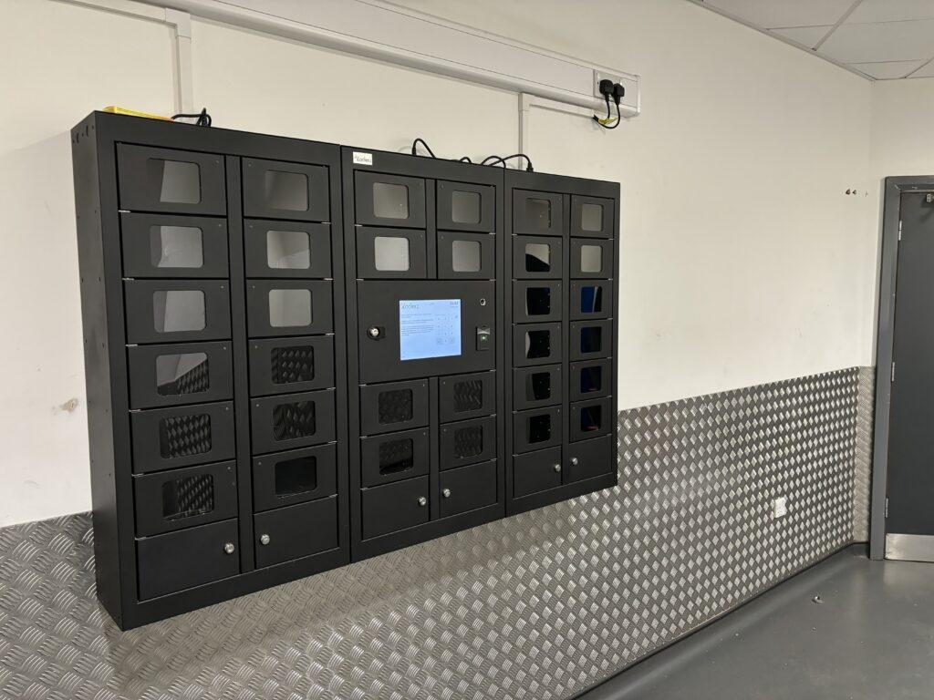 iLockerz scanner management system at Jaguar Land Rover (JLR), featuring clear-fronted compartments and a central touchscreen for secure checkout and automated tracking of handheld warehouse devices.